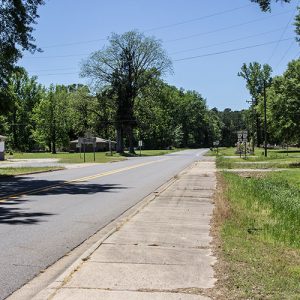 Two-lane rural road with single-story buildings on its left side