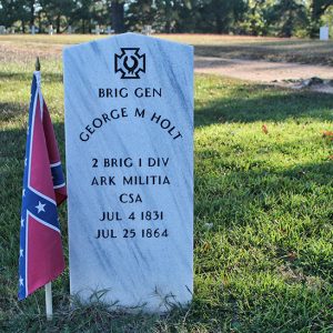 Engraved white gravestone in cemetery with Confederate Battle Flag in cemetery