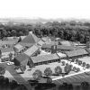 Model of convent with steeple and cross and pyramid shaped center building surrounded by trees