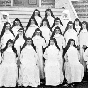 Group of white women in full habit posing on a staircase outside a brick building