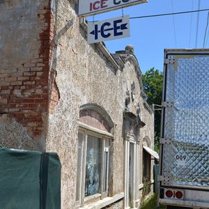 Brick storefront with hanging signs and semi-tuck trailer