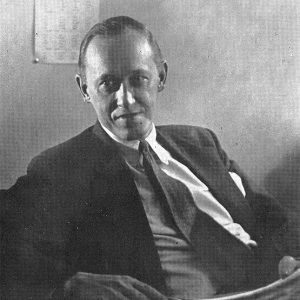 White man wearing suit and tie sitting at a desk