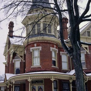 Multistory house with tower and wrap around covered porch in winter