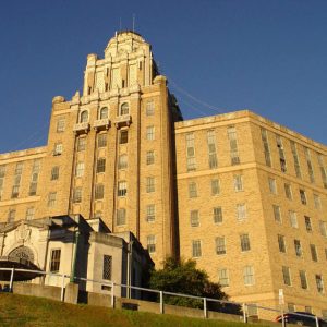 Tall building with rows of windows and flags in the foreground