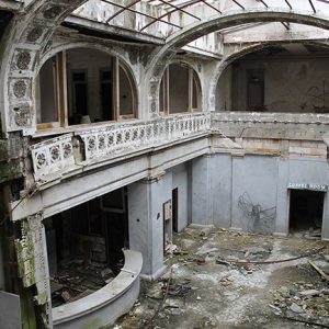 Inside abandoned two-story ornate hotel lobby with glass roof