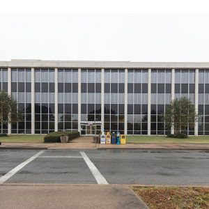 Cars parked on street outside multistory building with hanging glass windows