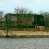 Multistory building with hanging glass walls and trees by a river