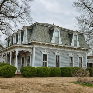 Side view of two-story house with windows and bushes