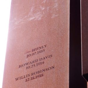 Rust-colored metal rectangle engraved with names and locations