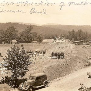 Road and bridge construction site with parked car and workers with horses