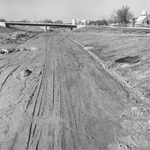 Pre-pavement highway with concrete bridge in the background