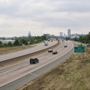 Busy interstate with State Capitol building and tall buildings in the distance