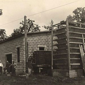 Men standing beside large brick structure