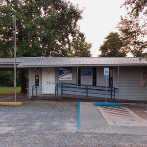 Single-story building with covered porch and car port on parking lot