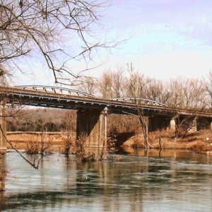 Concrete bridge over a river with trees and blue skies