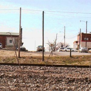 Railroad tracks with town buildings and cars in the background