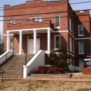 Three-story brick church with stairs and sign