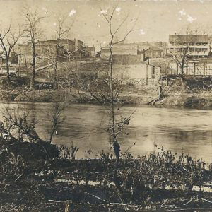 old faded photo of river with trees in the foreground and town in the background