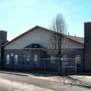 Single-story brick building with chain-link fence next to road