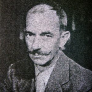 White man with curled up mustache in suit and tie