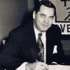 White man in suit and tie signing document