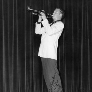 signed photo of young white man in white suit jacket playing trumpet