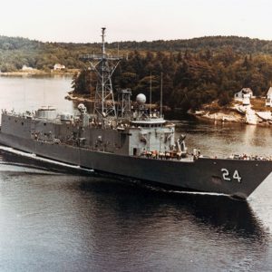 Naval ship on water with houses on shore nearby