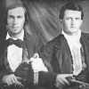 Two young white men in suits with knives in hand