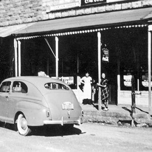 Two white women at storefront with car