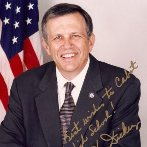 White man in suit and tie smiling with flag behind him signed "Best wishes to Cabot High School! Jay Dickey"