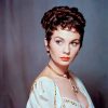 White woman with short curly hair in gold and white dress