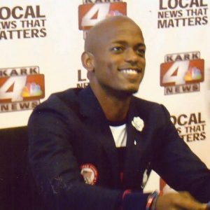 African-American man sitting and smiling in suit jacket