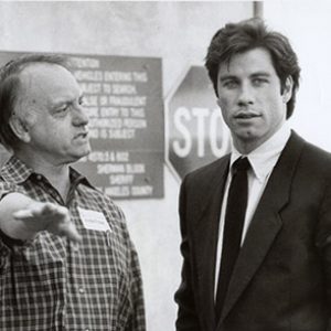 Older white man pointing and younger white man in suit and tie with traffic signs behind them