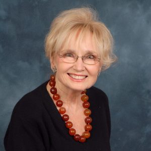 white woman in glasses wearing red beads around her neck and a black top