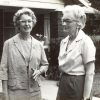 Pair of older white women with glasses standing outside house with covered porch