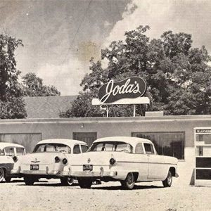 Cars and phone booth in front of restaurant "Joda's"