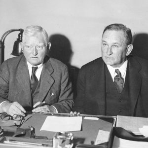 Two white men in suits seated at table