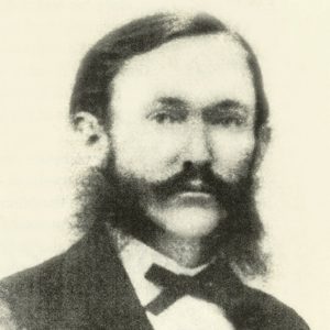 White man with mustache and sideburns in suit and bow tie