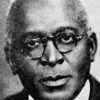 African-American man with round glasses in suit jacket and tie