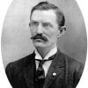 White man with mustache in suit and tie