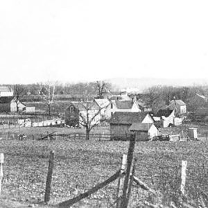 Houses and town buildings on dirt roads with fences