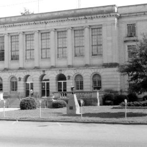 Three-story stone building with arched entrances and parking lot