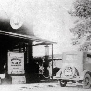 Cars parked outside service station and brick storefront on street