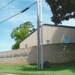 Single-story building with metal siding behind brick wall