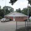 Brick building labeled "Joiner City Hall" with car in parking lot