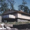 Multistory house with covered porch and balcony on hill with brick wall in the foreground