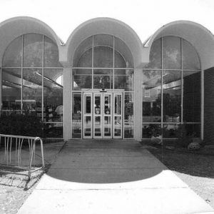 Close-up of brick building entrance with arched roofs and large windows