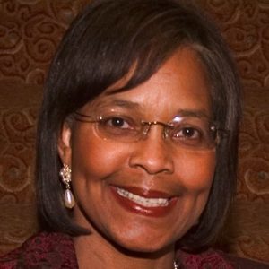 smiling black woman with straight hair glasses and necklace and earrings