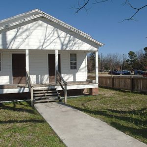 White wooden house with two front doors and porch swing