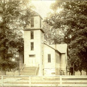 white wooden building with tower and stairs in front